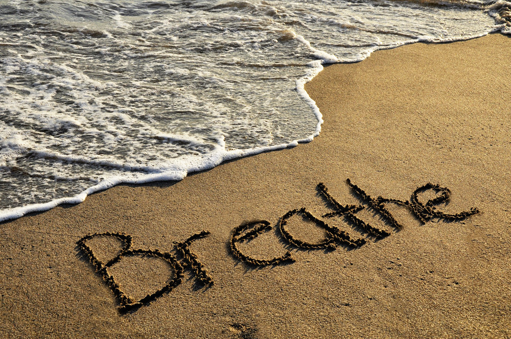 the word "breathe" drawn on a beach