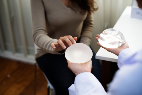 woman being shown two different implants by surgeon