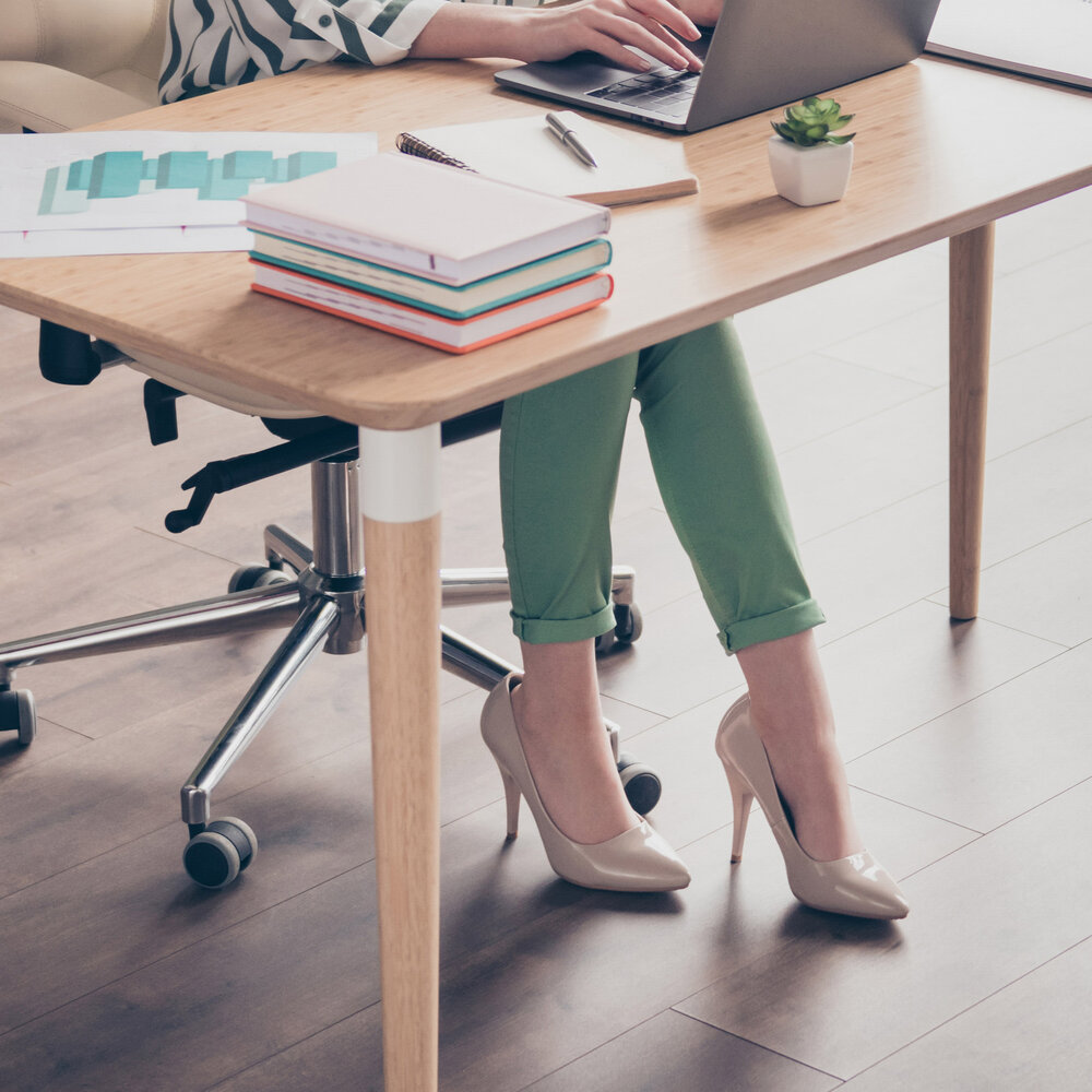 the legs of a woman sitting at a desk