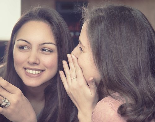 woman whispering to another woman