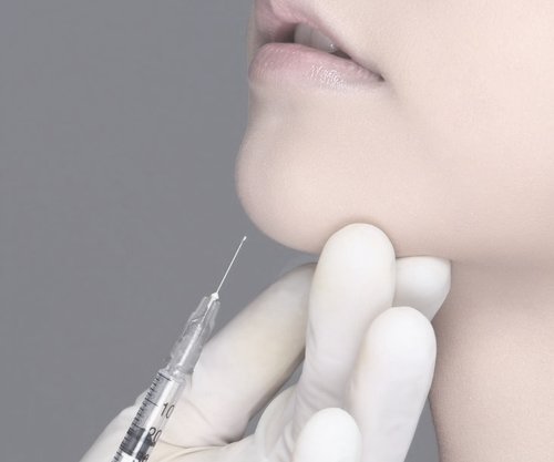 Doctor inserting syringe into woman's chin