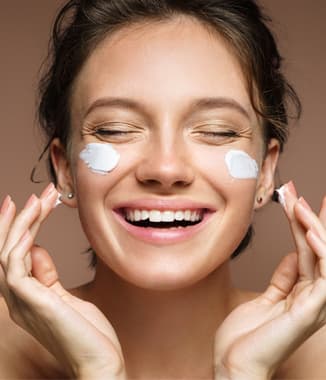 Woman applying cream to face and smiling